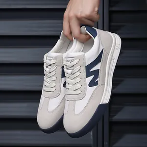 Detailed view of hand holding retro German Army trainers in grey and navy blue colorway