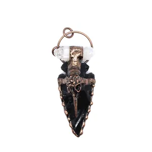Close-up detail of a gothic obsidian arrowhead pendant with raven skull and quartz point