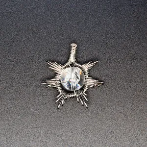 Macro view of a handmade wire-wrapped sunburst pendant with a clear natural stone
