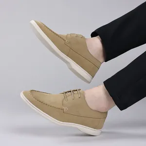Close-up side view of tan suede men's casual loafers with white soles worn by a model