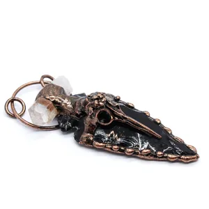 Detailed view of a gothic obsidian arrowhead pendant with a copper crow skull and raw crystals.