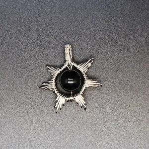 Detail of a handmade wire-wrapped sun pendant featuring a black natural stone center.