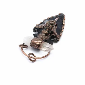 Detailed view of black obsidian arrowhead pendant with white crystal and crow skull