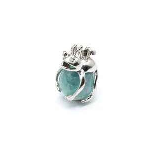 Detailed macro view of a silver frog prince pendant holding a green natural stone sphere
