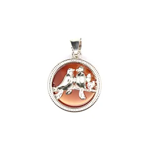 Vue détaillée d'un pendentif rond en argent avec deux oiseaux et une pierre d'agate rouge.