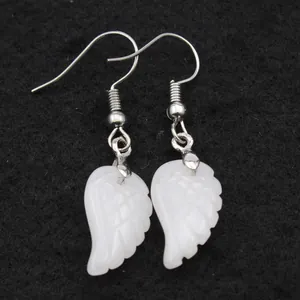 Vista macro detallada de pendientes de cuarzo blanco natural con forma de alas de ángel