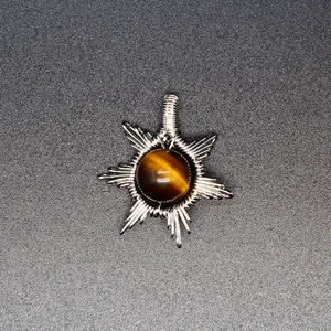 Detailed close-up of handmade silver wire-wrapped sun pendant with a tiger eye stone center