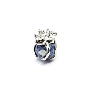 Detailed view of frog prince pendant holding blue natural stone sphere