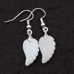 Detalle de pendientes de gancho de piedra natural blanca con forma de ala en tela