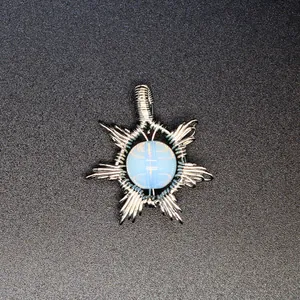 Detailed macro view of a handmade silver wire-wrapped sun pendant with an opalite stone