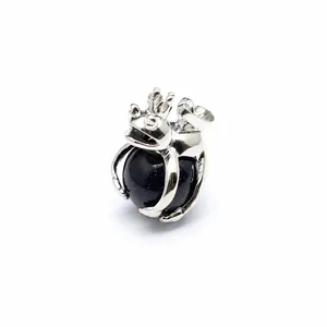 Close-up of silver frog prince pendant holding a sparkling blue goldstone bead
