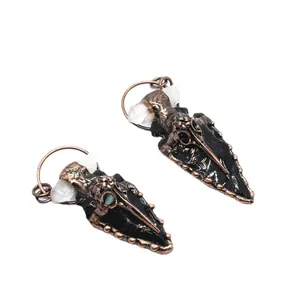 Obsidian and crystal arrowhead pendants with vintage crow skull detail on white background
