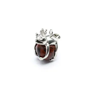 Detailed shot of a silver frog prince pendant clutching a reddish-brown natural stone ball.
