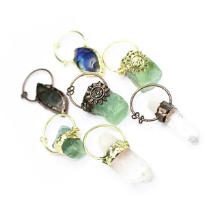 Close-up of raw crystal pendants including labradorite and fluorite with sun motifs