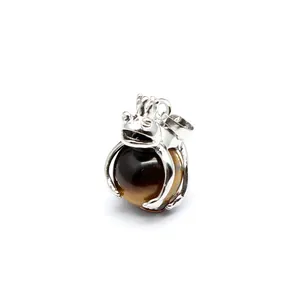 Detailed macro view of a silver frog prince jewelry pendant holding a polished tiger eye bead