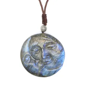 Macro detail of hand-carved labradorite pendant with blue moon face and wing motifs