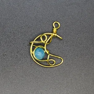 Macro view of a gold wire-wrapped crescent moon pendant with a blue natural stone.