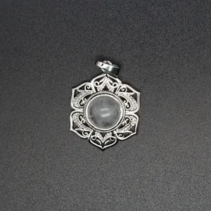 Vue détaillée d'un pendentif en dentelle florale argentée avec une perle de cristal translucide