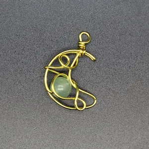 Close-up of hand-woven gold wire moon pendant featuring a green natural stone bead