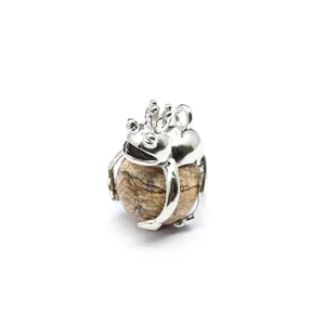 Close-up of a silver frog prince pendant holding a natural patterned stone sphere