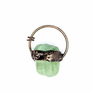 Close-up detail of a raw green crystal gemstone pendant with rustic bronze metal wrapping
