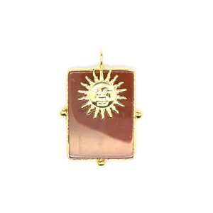 Gros plan d'un grand pendentif rectangulaire en cornaline avec un motif de soleil doré complexe