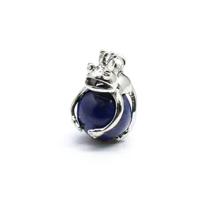 Detailed macro view of a silver frog prince pendant hugging a blue lapis lazuli sphere.