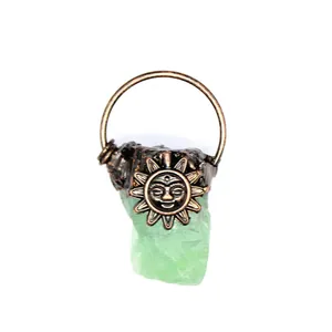 Detailed macro view of a raw green crystal pendant with an antique bronze sun face carving