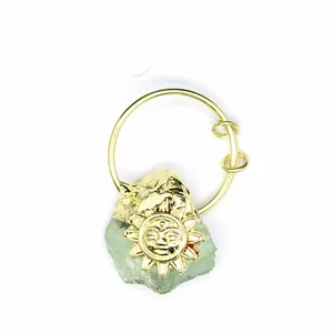 Detail showing the intricate golden sun face charm paired with a raw green crystal stone