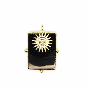 Détail d'un pendentif rectangulaire en agate noire avec un motif de soleil doré.