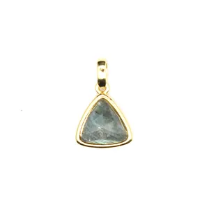 Macro view of a faceted triangle natural stone pendant set in a gold bezel bail