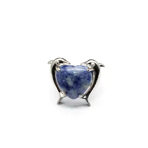 Dettaglio dell'anello in pietra naturale a cuore con design a delfino argentato e fascia regolabile.