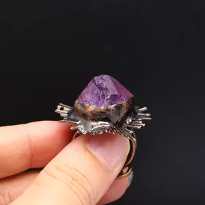 Primer plano de anillo vintage artesanal con piedra en bruto púrpura y bronce rústico.