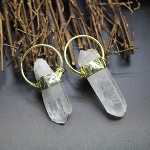 Macro detail of natural clear quartz crystal point pendant with textured gold hoop