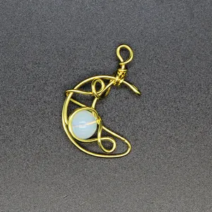 Detail view of a handcrafted golden wire-wrapped crescent moon pendant with opal stone