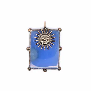 Détail macro du motif visage soleil en bronze vintage sur pendentif en agate bleue