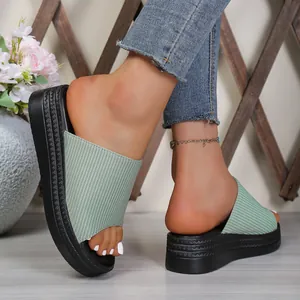Detail view of light green striped fabric platform slides with thick black sole for women.