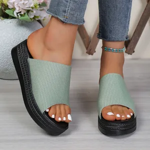 Close-up view of women's light green ribbed fabric platform slides worn on feet.