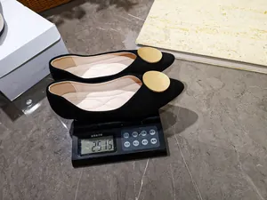 Vista detallada de manoletinas negras puntiagudas en una báscula que pesa 251,5 g.