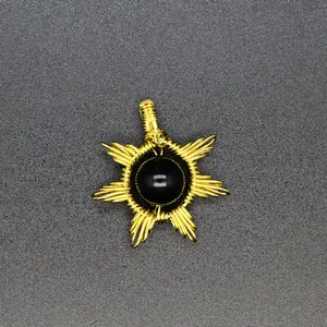 Close-up of a handmade gold wire-wrapped sun pendant featuring a polished black gemstone.