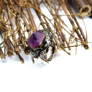 Primer plano de anillo vintage con cristal violeta en bruto y engaste de sol texturizado