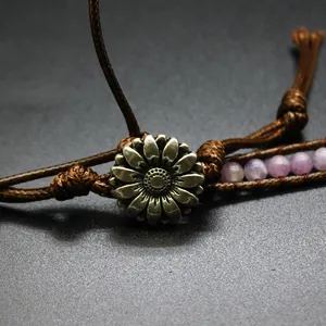Close-up detail of vintage metal daisy charm on handmade braided natural stone wrap bracelet