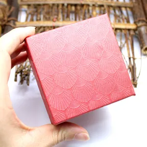 Detailed view of a red square jewelry gift box with an elegant shell-patterned texture.