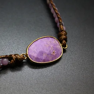 Macro view of a handmade woven cord bracelet with a faceted purple gemstone focal