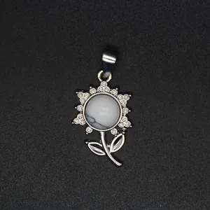 Detailansicht eines silbernen Blumenanhängers mit weißem Stein und Pavé-Besatz.