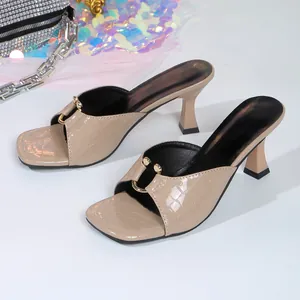 Detailed view of nude crocodile embossed square-toe high-heel sandals with gold hardware.