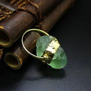 Detailed view of a raw natural green crystal stone pendant wrapped in gold plating.