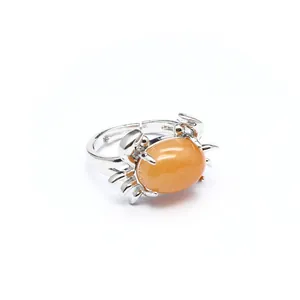 Detailansicht eines silbernen Krabbenrings mit einem polierten orangefarbenen Opalstein
