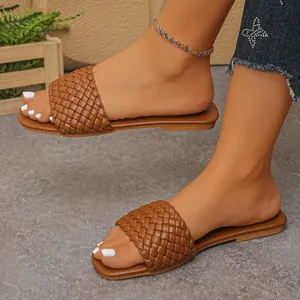 Detailed view of women's brown woven flat sandals featuring a stylish Roman strap design