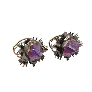 Anillos vintage con piedra púrpura bruta y engaste de rayos de sol de cobre sobre fondo blanco.